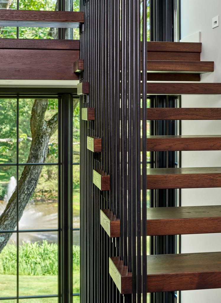 Detail of contemporary floating stair suspended by dark metal rods with wood treads