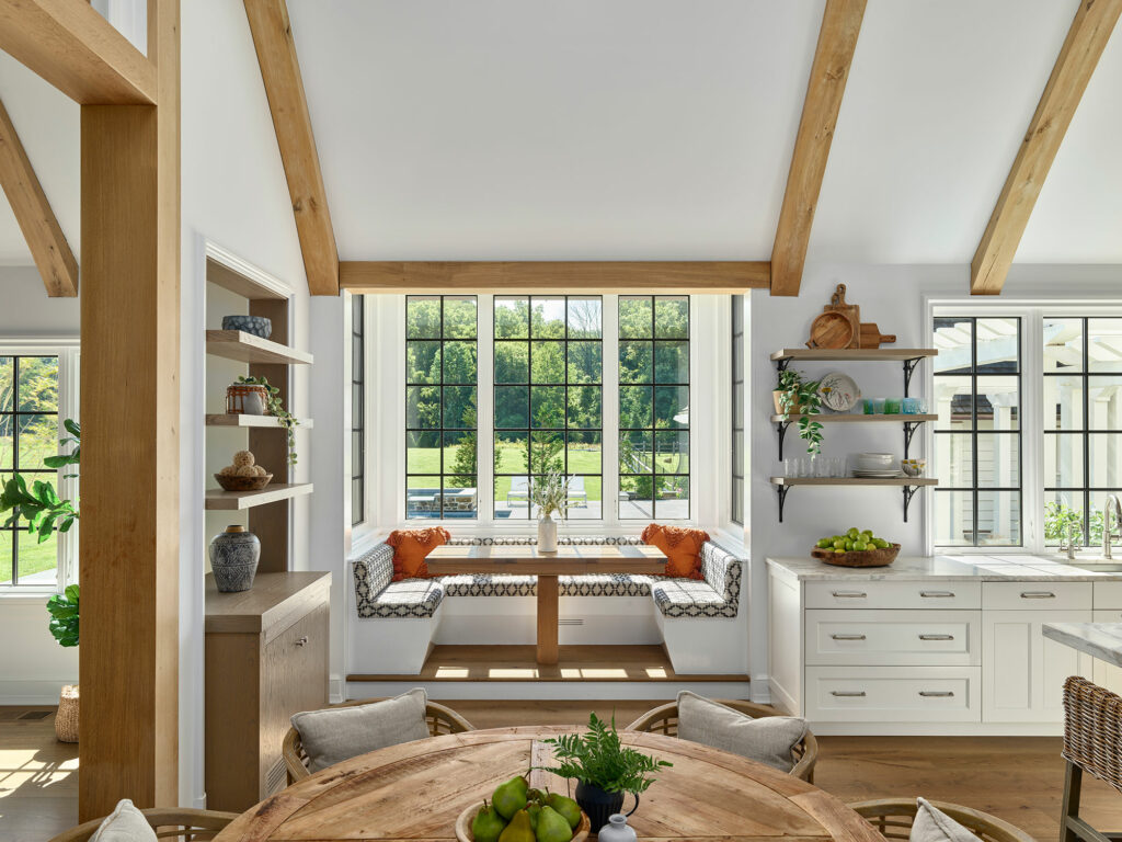 Built in breakfast nook in a contemporary farmhouse with white walls, black frame windows and timber frame vaulted ceiling.