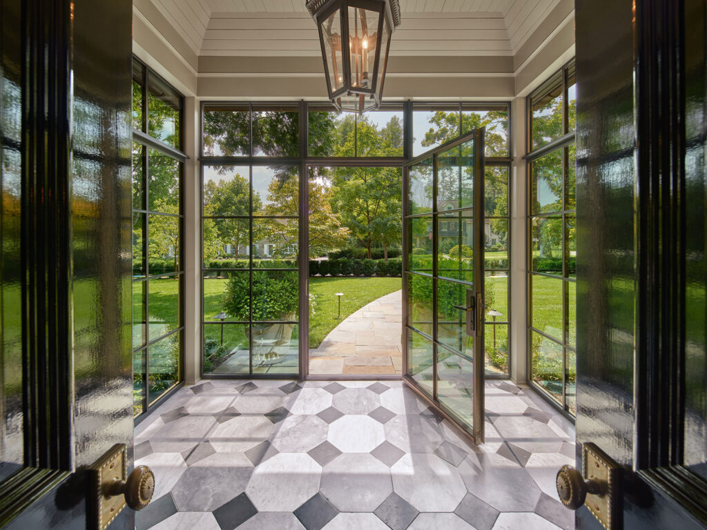 view through glass and steel enclosed portico to front yard beyond