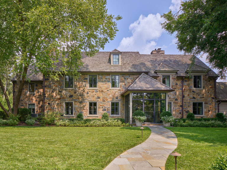 front elevation of a 1950s stone colonial revival home with enclosed portico following renovations